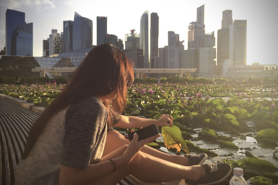 banner-image-A girl sits by the ArtScience Museum lily pond, enjoying the Singapore skyline